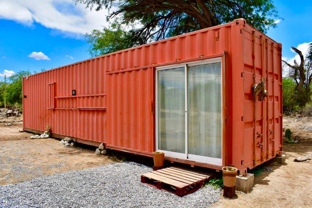 un conteneur de transport orange avec un banc devant dans l'établissement Tampu, the Container House, à Cafayate