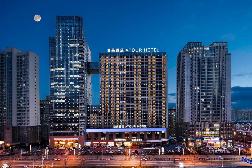 een groep van hoge gebouwen in een stad 's nachts bij Atour Hotel Dalian Development Zone in Dalian