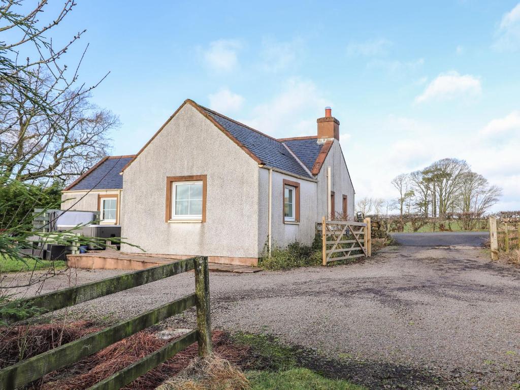 une maison blanche avec une clôture devant elle dans l'établissement Grey Craig Cottage, à Lockerbie