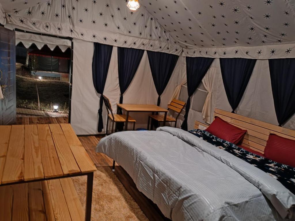 een slaapkamer met een bed en een tafel in een tent bij Imilia Camps in Bir