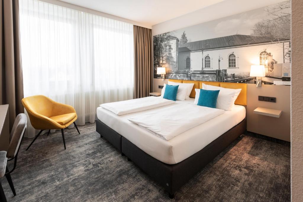 a hotel room with a bed and a yellow chair at Best Western Hotel am Europaplatz in Königsbrunn