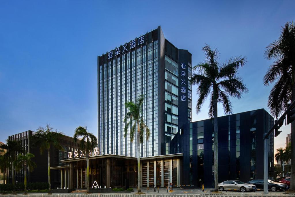 a tall building with palm trees in front of it at Atour X Hotel Zhuhai Lover Road Red Wave Bay Beach Seaview in Zhuhai