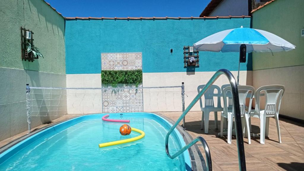 a swimming pool with an umbrella and an inflatable at Casa de temporada Guarapari Casa Dule in Guarapari