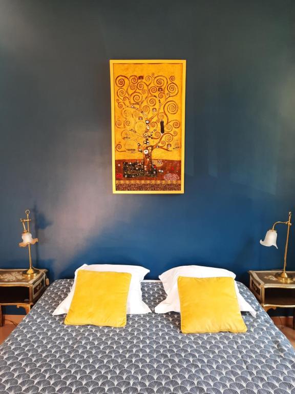 a blue bedroom with a bed with two yellow pillows at Le Clos des Chênes in Lagarde-Paréol