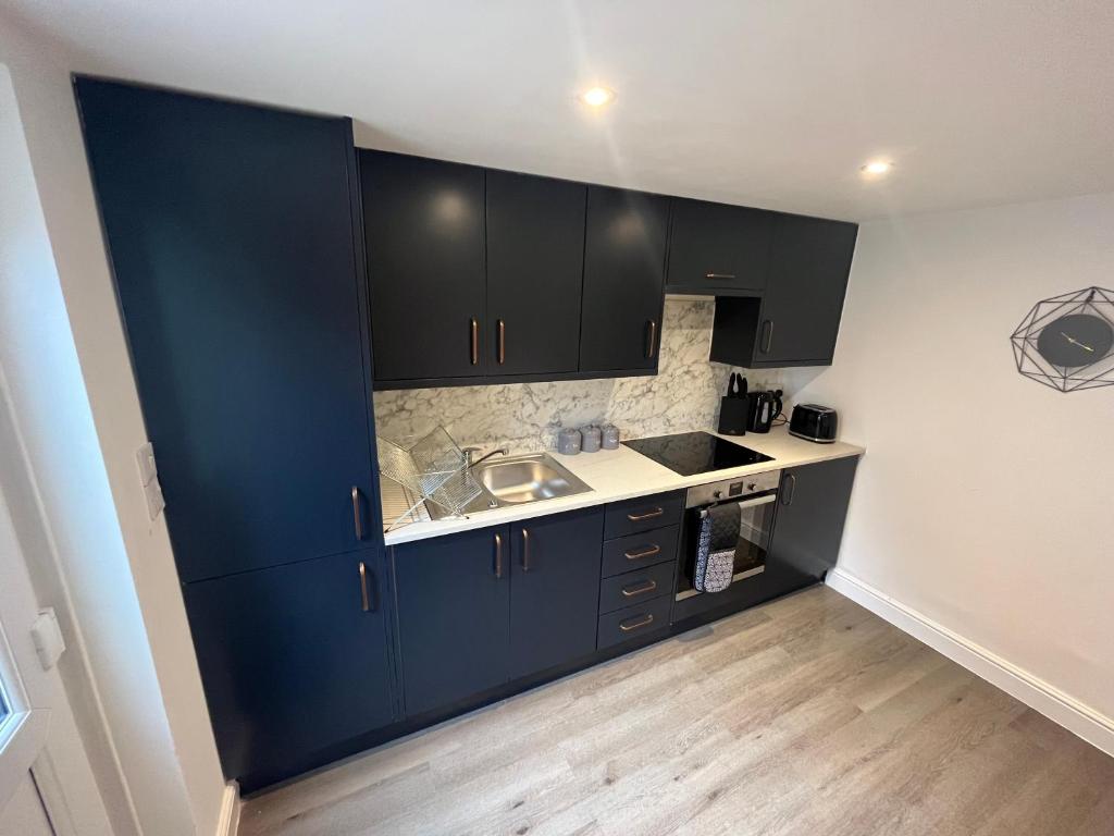 una cocina con armarios negros y fregadero en Corner Stone House - Apartment 2, en Great Yarmouth