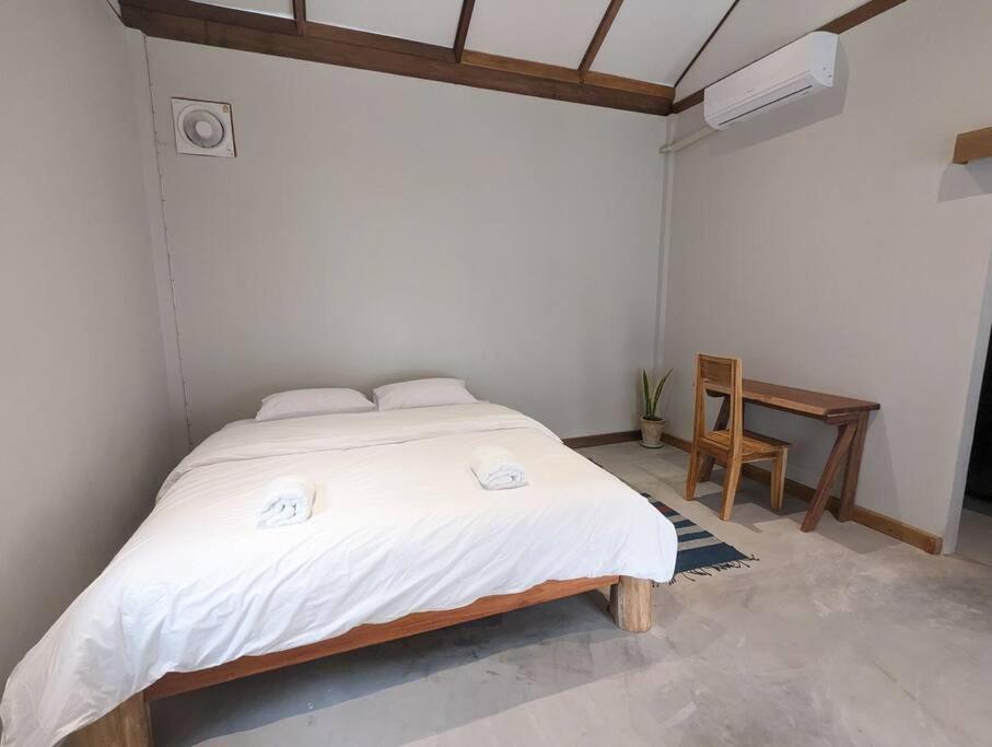 a bedroom with a large white bed with a desk at Maison moderne proche du centre-ville in Luang Prabang