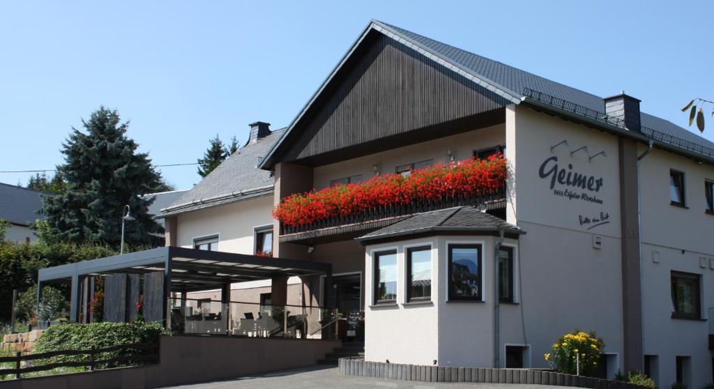 een gebouw met rode bloemen aan de zijkant bij Gasthaus Pension Geimer in Plütscheid