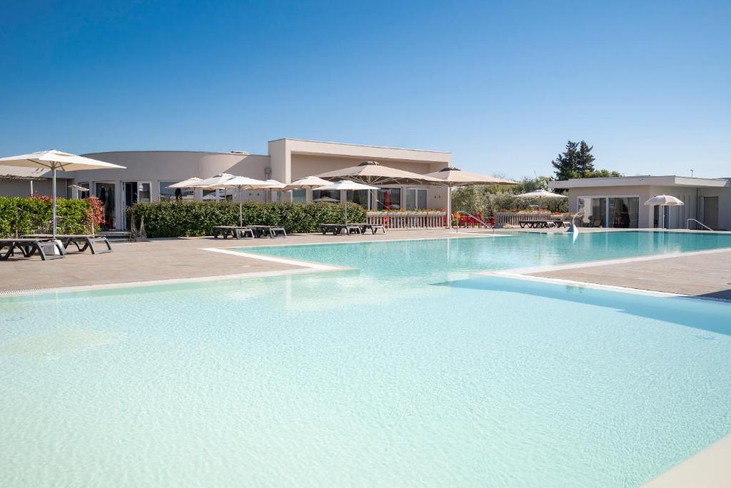 a large swimming pool in a resort with umbrellas at Vada Village in Vada