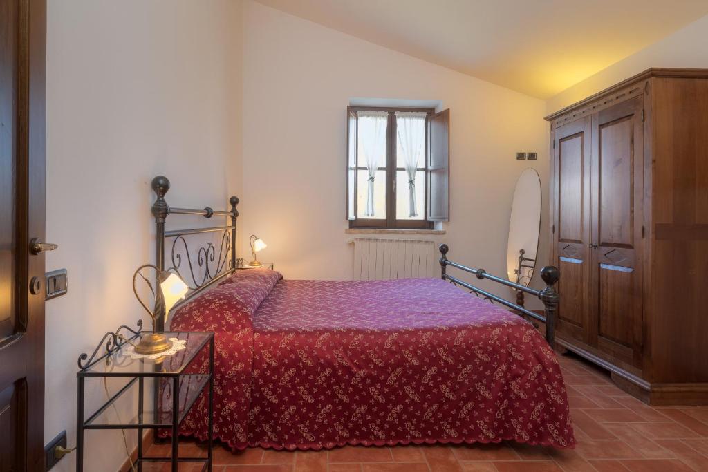 a bedroom with a bed with a red bedspread at Castello di Pupaggi in Sellano