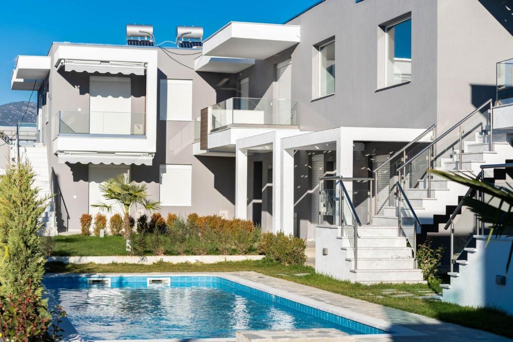 uma casa com uma piscina em frente em Ofrynio Luxury Apartments & Pool em Ofrínion