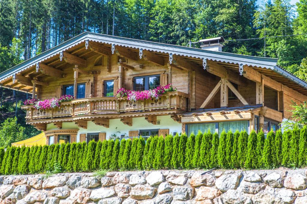 a wooden house with a balcony on top of a stone wall at Hauser Kathrin und Martin in Fieberbrunn