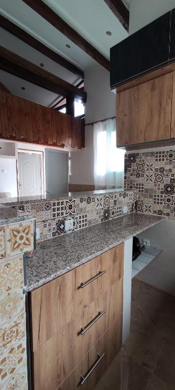 a kitchen with wooden cabinets and tiles on the wall at Cosy house in Alger