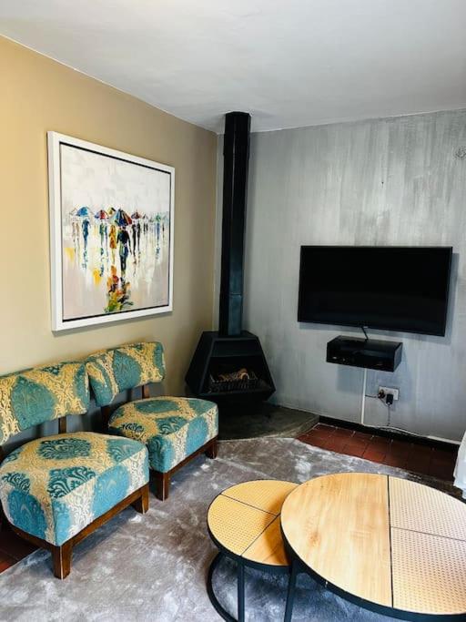 a living room with a couch and a table and a tv at A Cozy Secure 2-Bed Apartment with a lovely garden in Gaborone