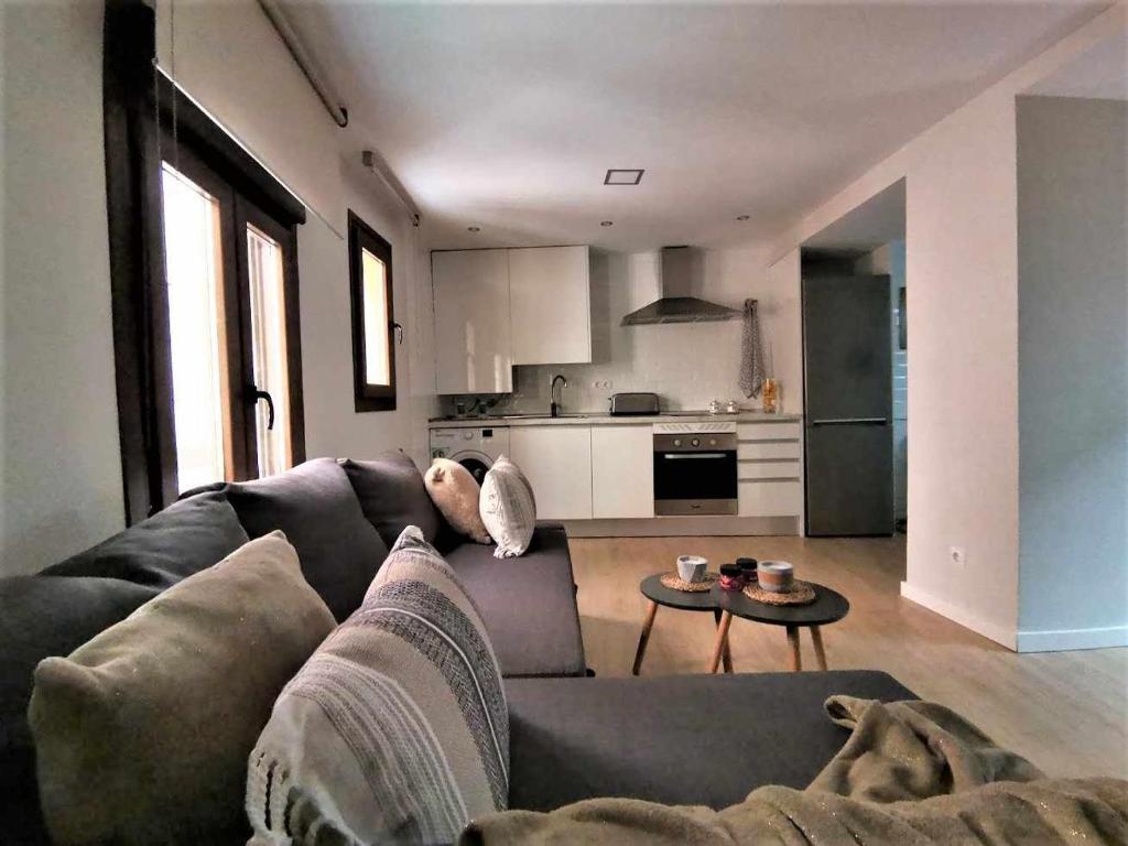 ein Wohnzimmer mit einem Sofa und einem Tisch in der Unterkunft Apartamento Ilarcuris con patio privado in Toledo
