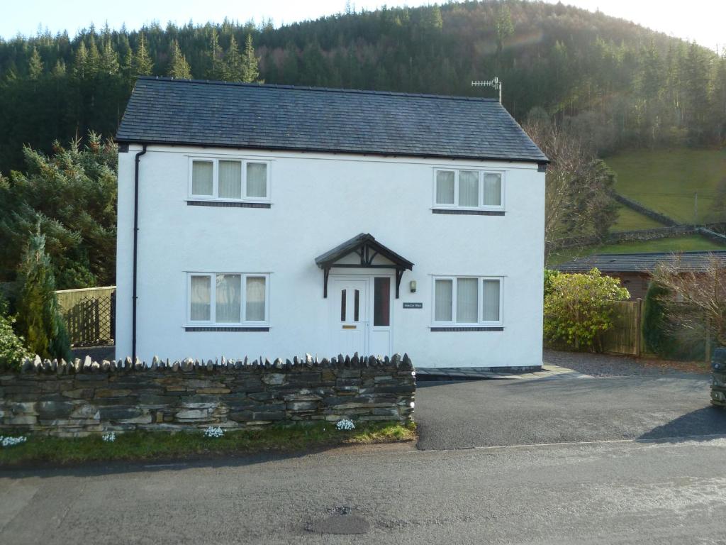 a white house with a stone wall at Hendre Wen holiday cottage in Betws-y-coed