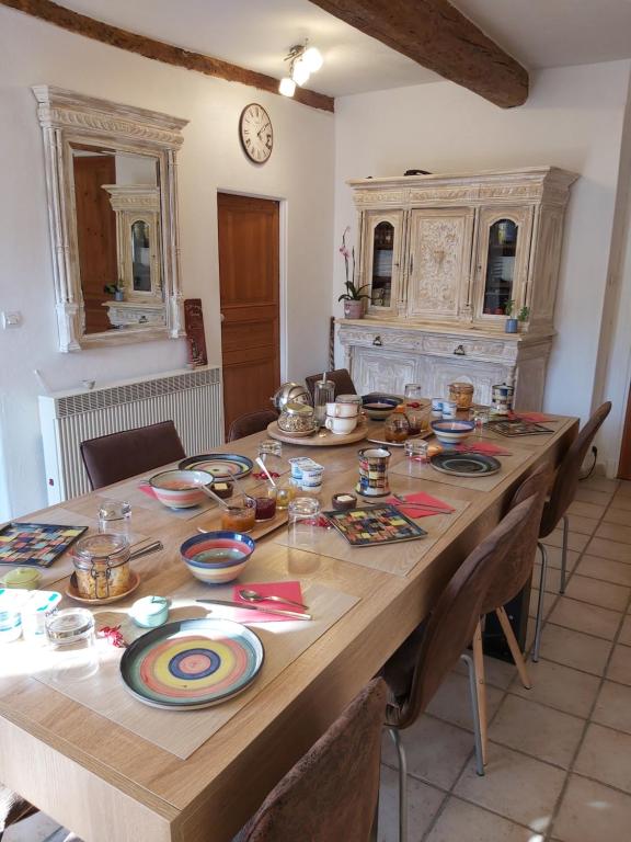 a large wooden table with plates and bowls on it at B&B Le Rupicapra in Roubion