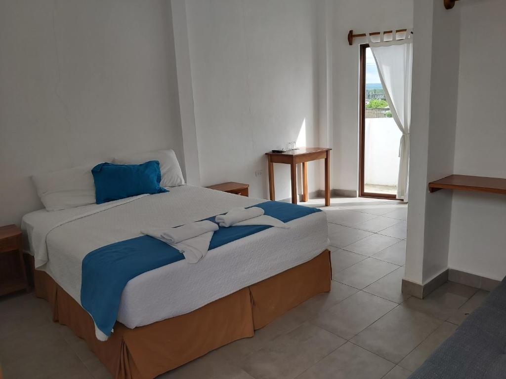1 dormitorio con 1 cama grande con sábanas azules y blancas en Galapagos Native, en Puerto Ayora