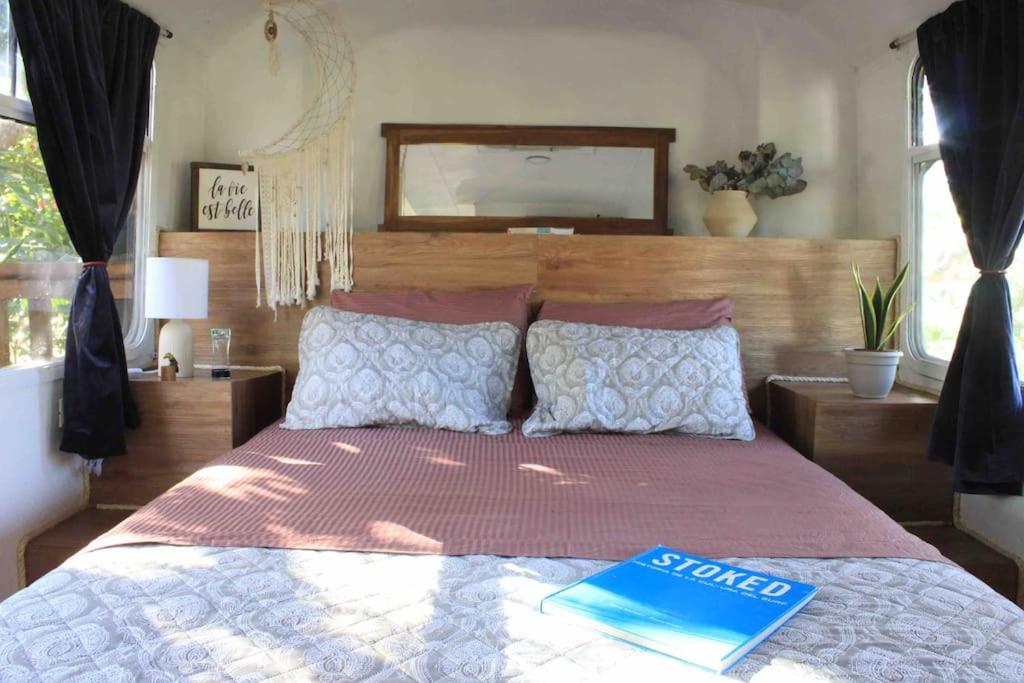 a bedroom with a large bed with a book on it at Casa Bus los Guanacastes in Veintisiete de Abril