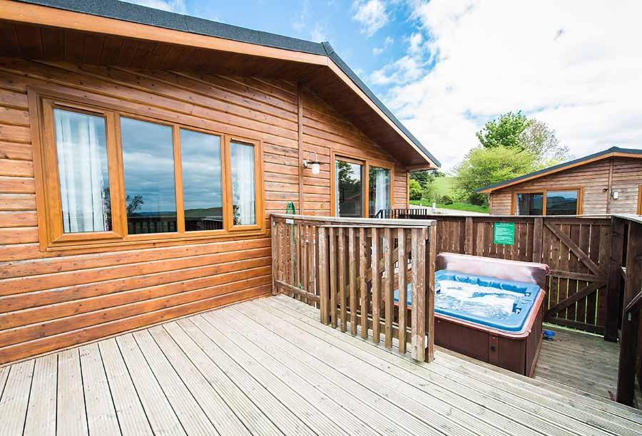 um deque de madeira com uma banheira de hidromassagem numa casa em Skylark Lodge with Hot Tub em Cupar
