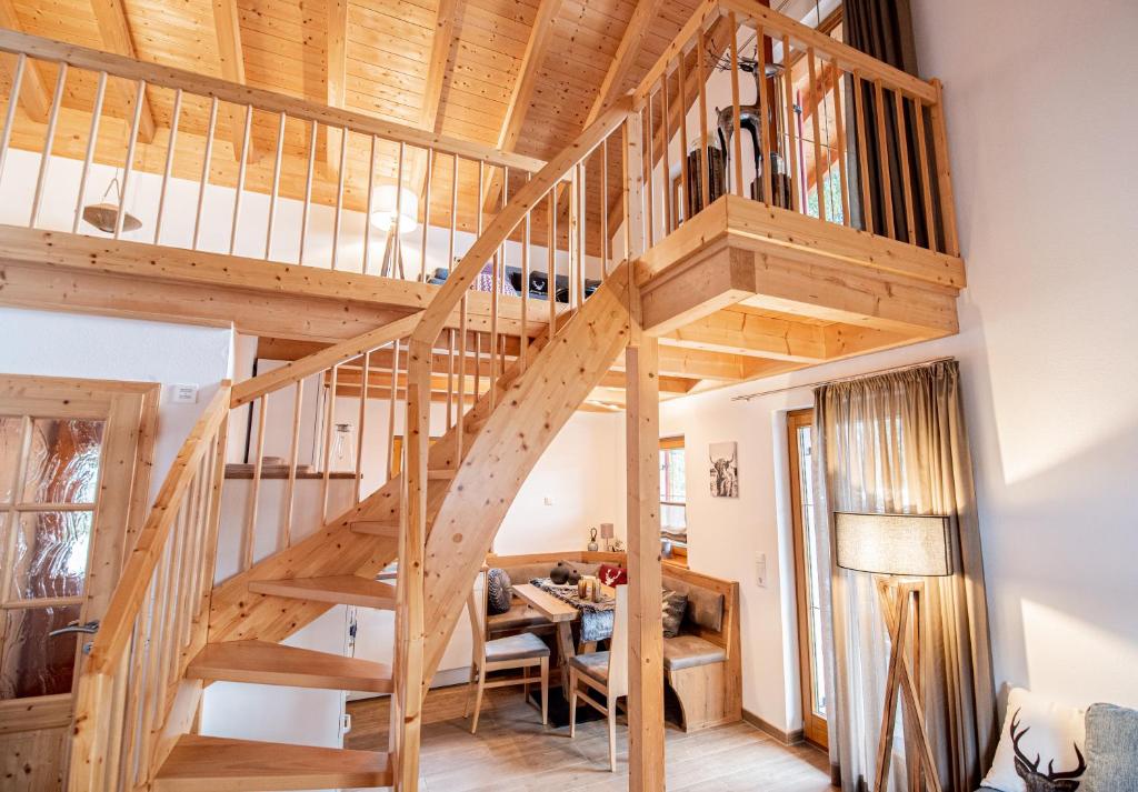 a wooden spiral staircase in a living room with a table at Hirsch Chalet #Sauna in Lechbruck