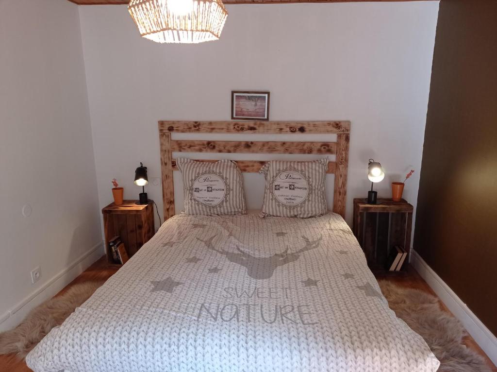 - une chambre avec un grand lit et une tête de lit en bois dans l'établissement Appartement cosy avec son charme ancien., à Saint-Claude