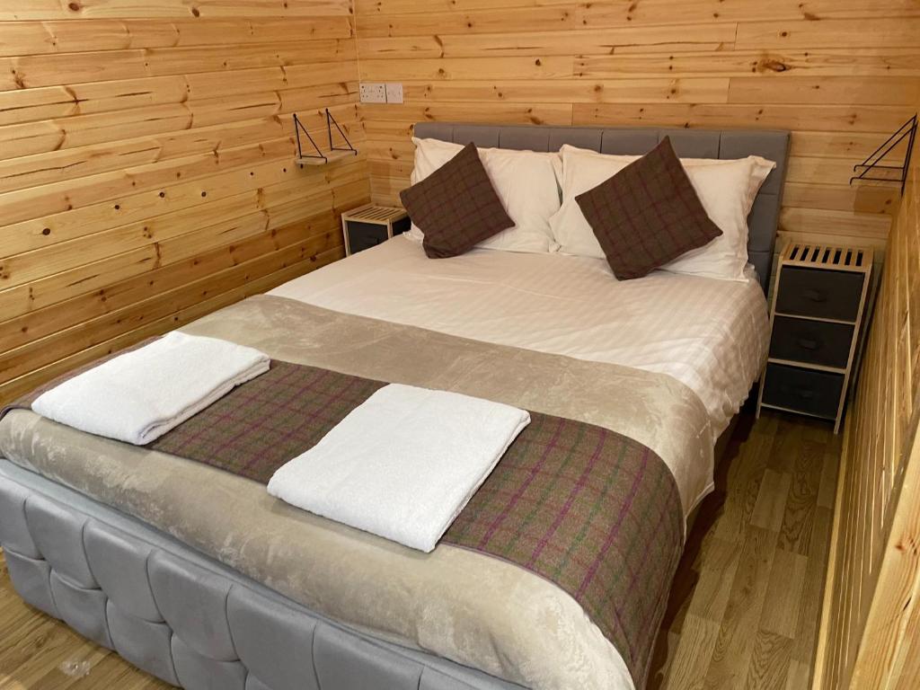 a large bed in a room with wooden walls at Fox's Den in Bathgate