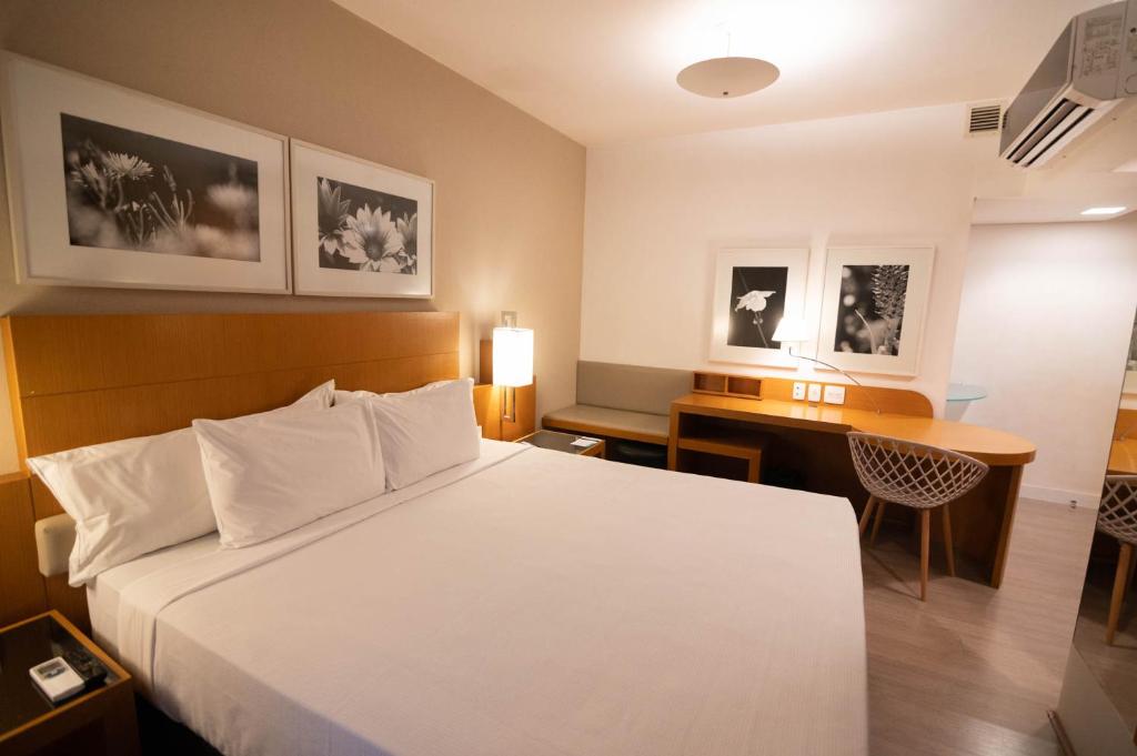 a hotel room with a bed and a desk at H2 Platinum Lourdes in Belo Horizonte