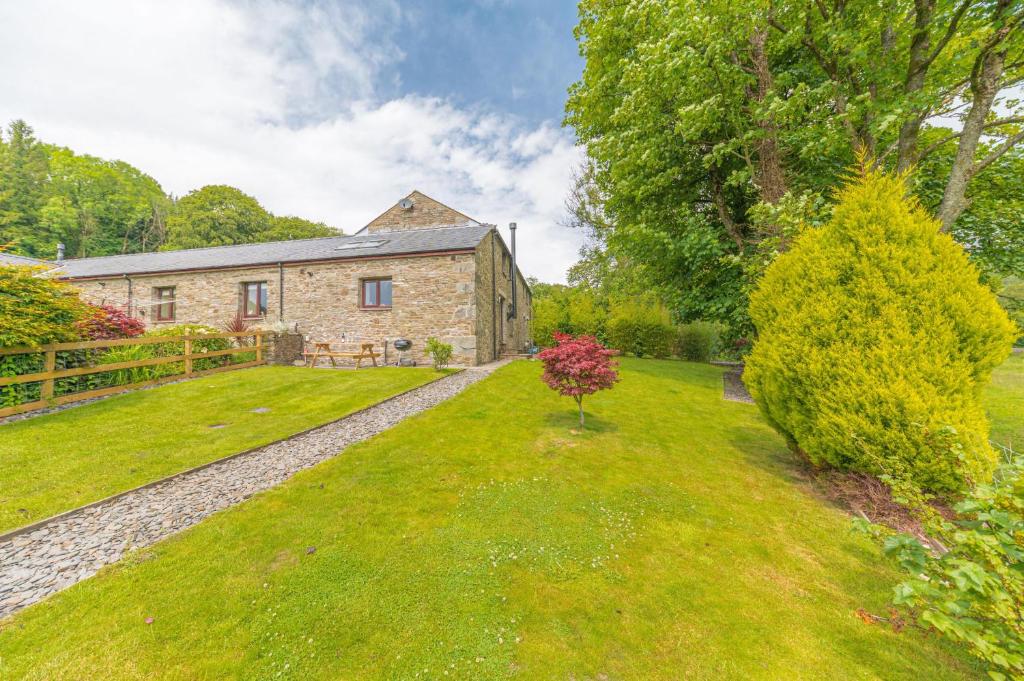 an exterior view of a stone house with a yard at Cow Barn, Duddon Bridge in Broughton in Furness