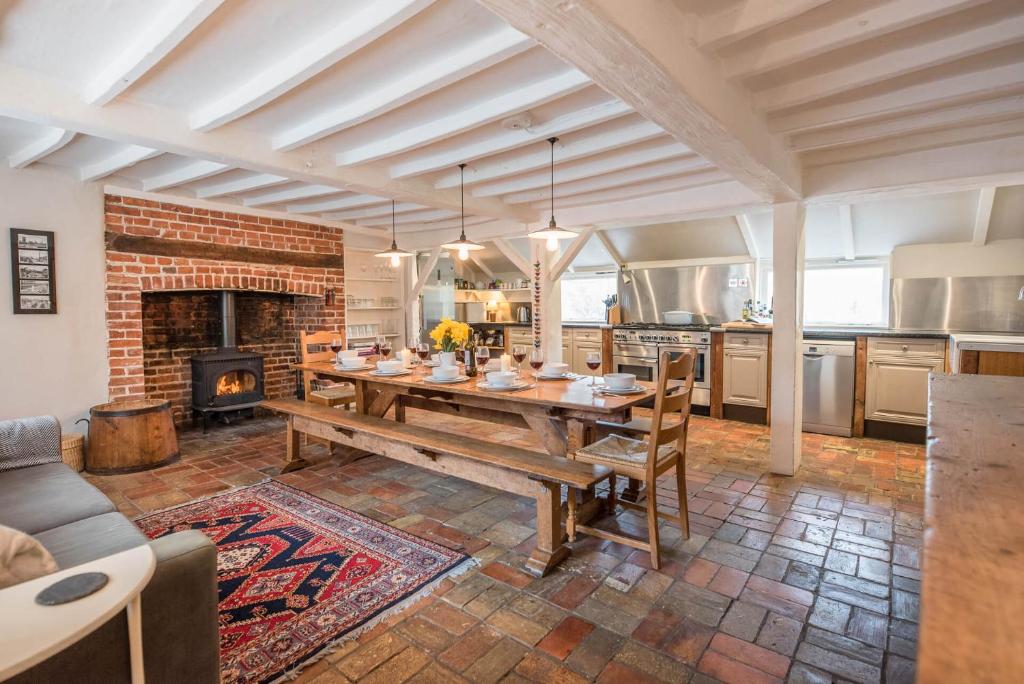 a kitchen with a wooden table and a fireplace at Ivy House Mells in Halesworth