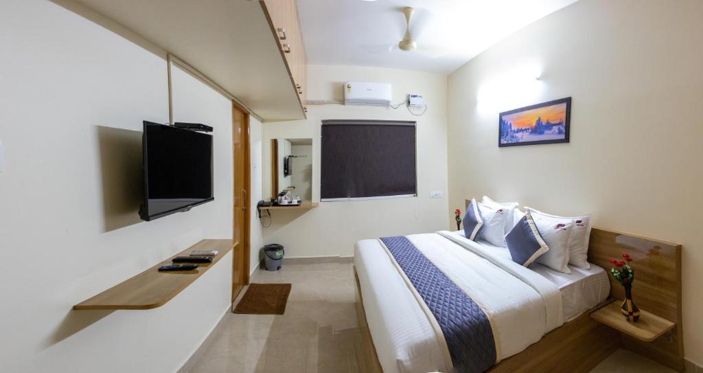 ein Schlafzimmer mit einem großen Bett und einem TV in der Unterkunft Richinn Palace home stay in Chennai