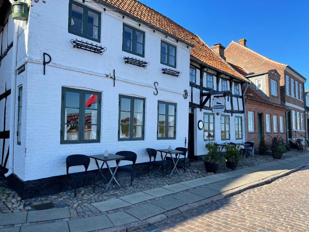 een wit gebouw met tafels en stoelen in een straat bij Restaurant Sælhunden in Ribe