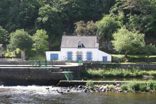 a white house sitting on the side of a river at Chambre d'hôtes dans maison éclusière in Hennebont