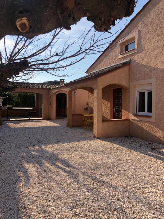 uma casa com uma entrada de cascalho em frente em AU MIMOSA - Gîte Le Murier em Passa