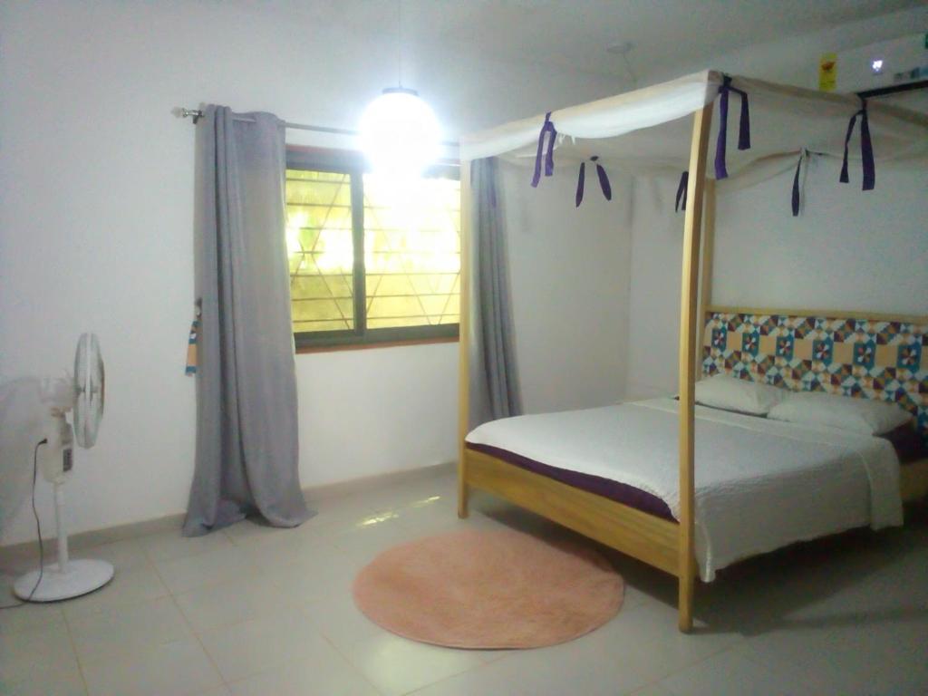 a bedroom with a canopy bed and a window at Kokrobitey Apartments-GAL in Accra