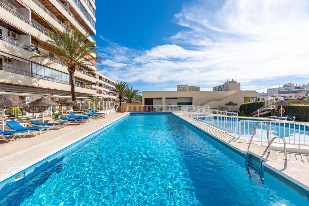 a swimming pool with blue chairs and a building at La Nogalera - Sea view apartment in the heart of Torremolinos in Torremolinos