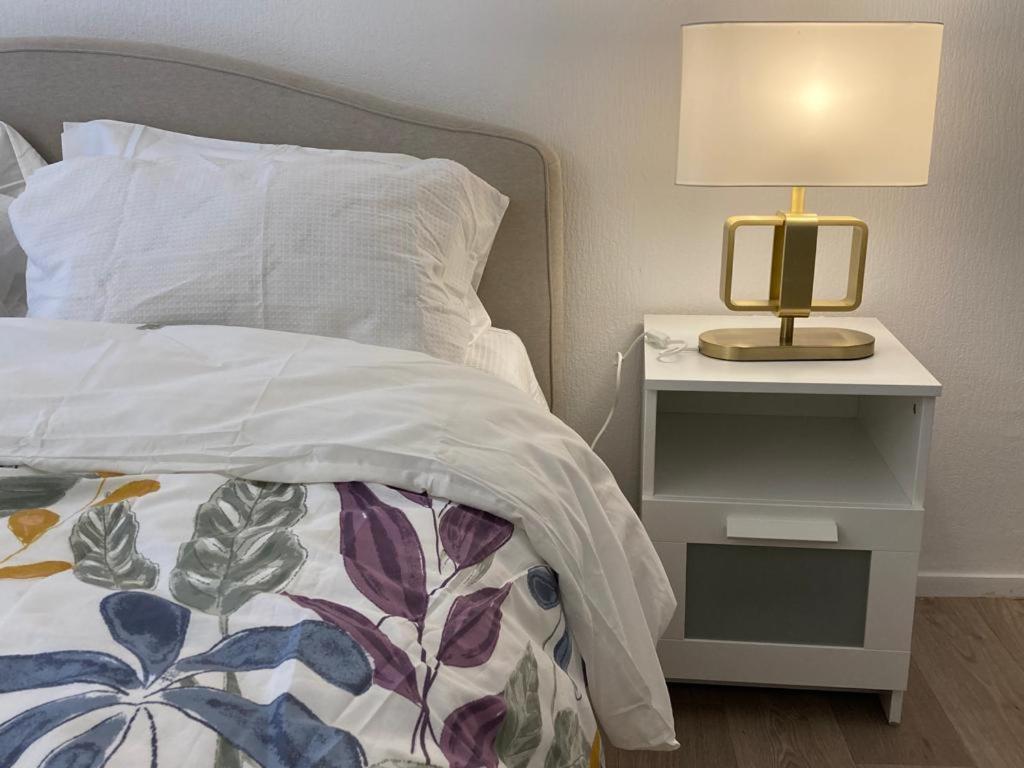 een bed met een nachtkastje met een lamp erop bij Appartement entier avec parking gratuit proche de Paris et Aéroport d'Orly in Thiais