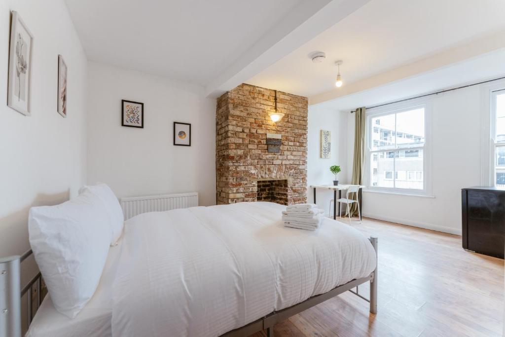 1 dormitorio con cama blanca y chimenea en Bethnal Green beds to stay, en Londres