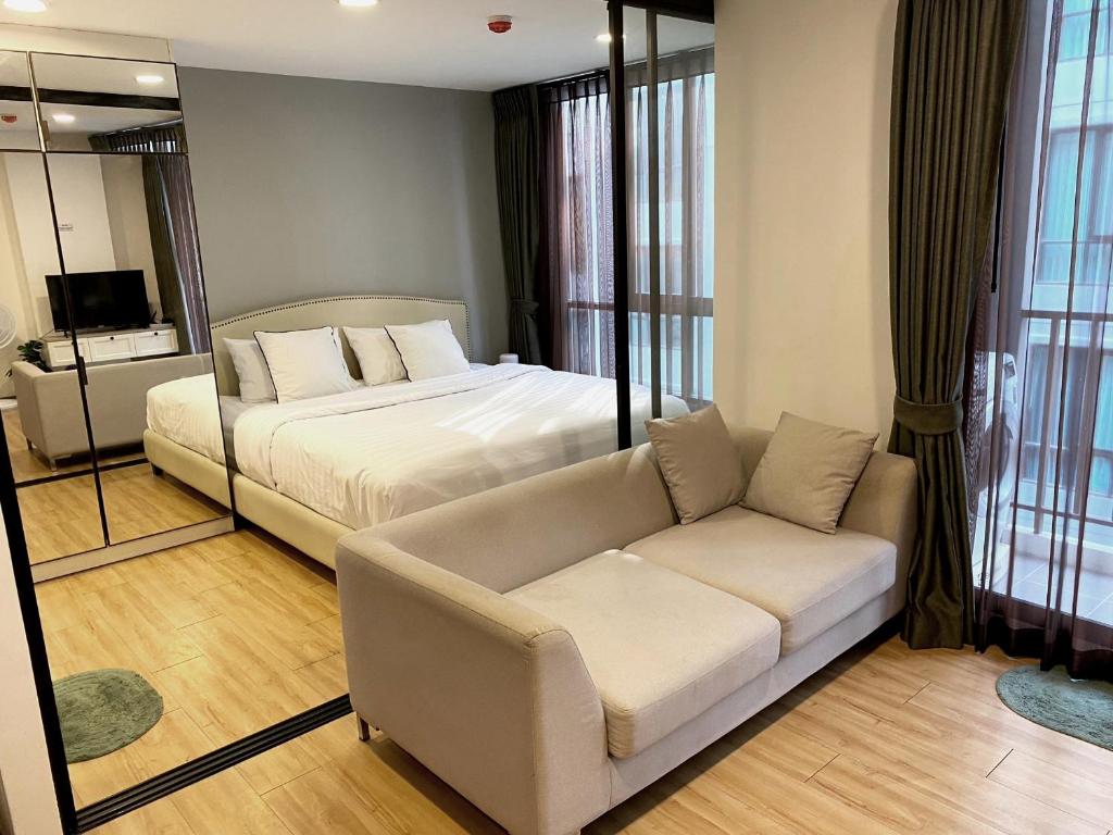 a bedroom with a bed and a couch and a mirror at Notthing Hill Charoenkrung93 Condominium in Godown
