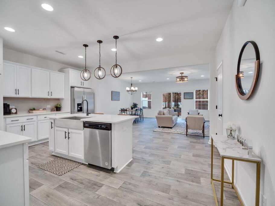 eine Küche mit weißen Schränken und ein Wohnzimmer in der Unterkunft Gorgeous New Townhome/Charlotte! in Charlotte