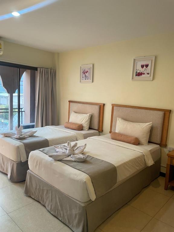 a hotel room with two beds with flowers on them at Babylon Residence Inn pattaya in Pattaya South