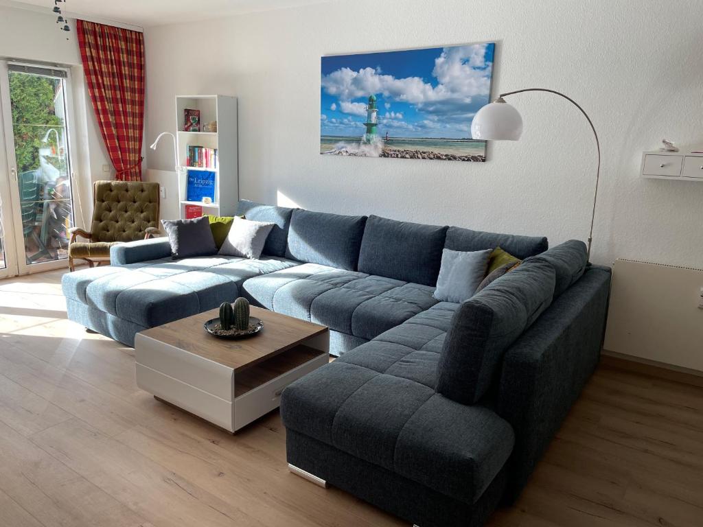 a living room with a blue couch and a table at Ostsee-Ferienwohnung-Lipsia in Ostseebad Nienhagen