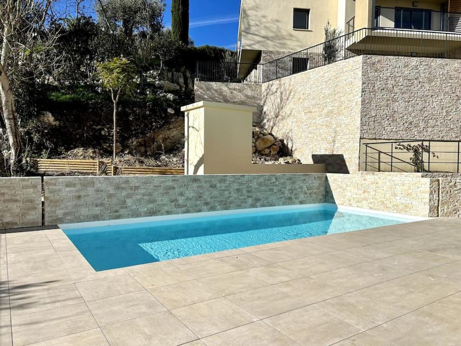 una piscina blu di fronte a una casa di Le Lily - T2 neuf vue mer a Èze