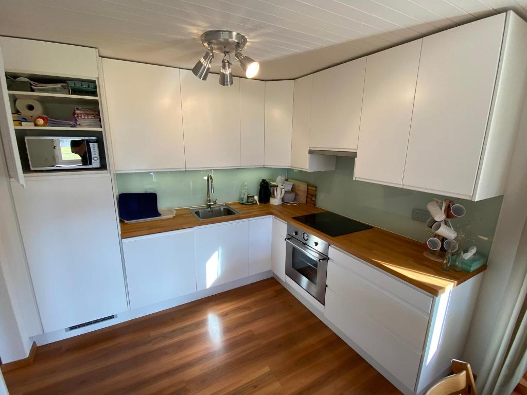 una piccola cucina con armadietti bianchi e pavimenti in legno di Apartment Arvenbüel-Flüügespitz ad Amden