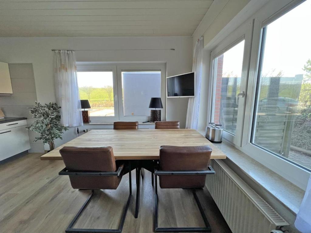 ein Esszimmer mit einem Tisch, Stühlen und Fenstern in der Unterkunft Deichblick 4 in Norddeich- Urlaub und Erholung am Strand in Norden