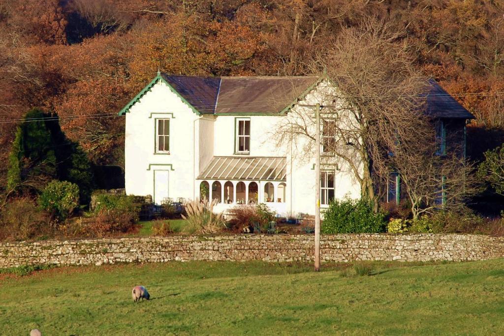 a white house in a field next to a stone wall at The Old Rectory in Coniston