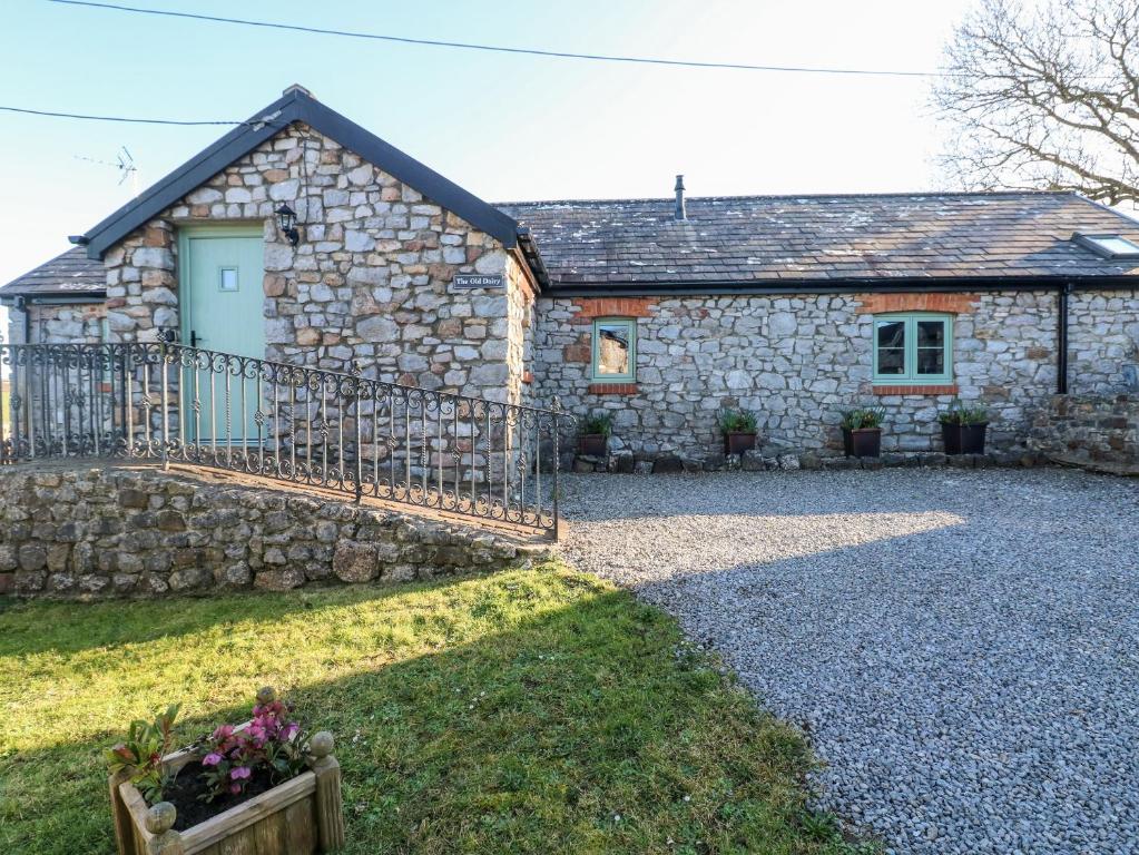 a stone house with a gate and a stone wall at Old Dairy in Knelston