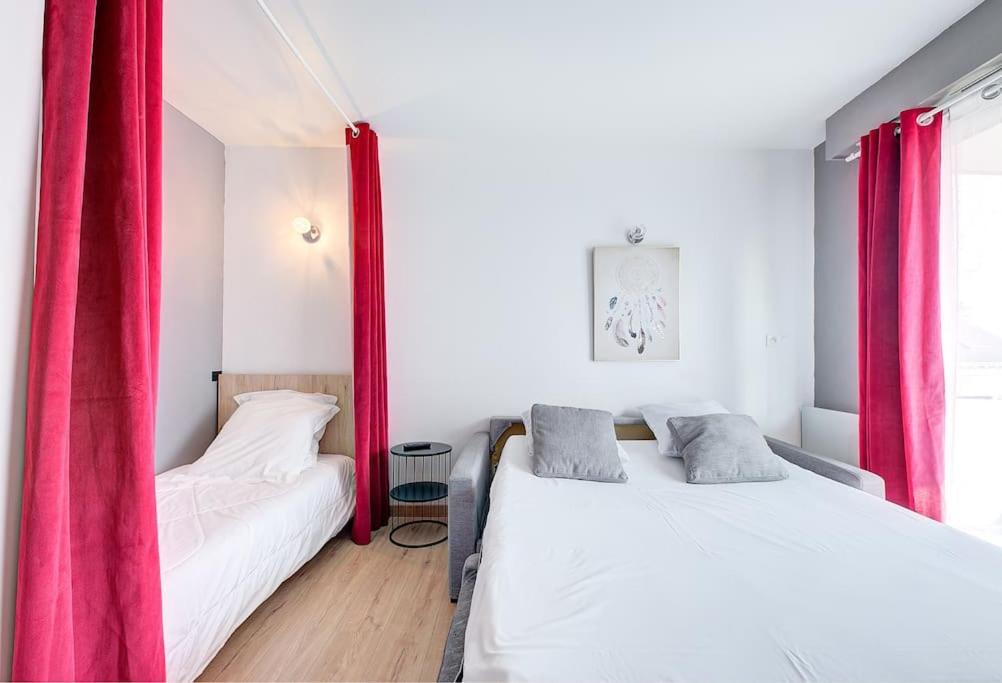 2 camas en una habitación con cortinas rojas en Studio Grammont 4 en Tours