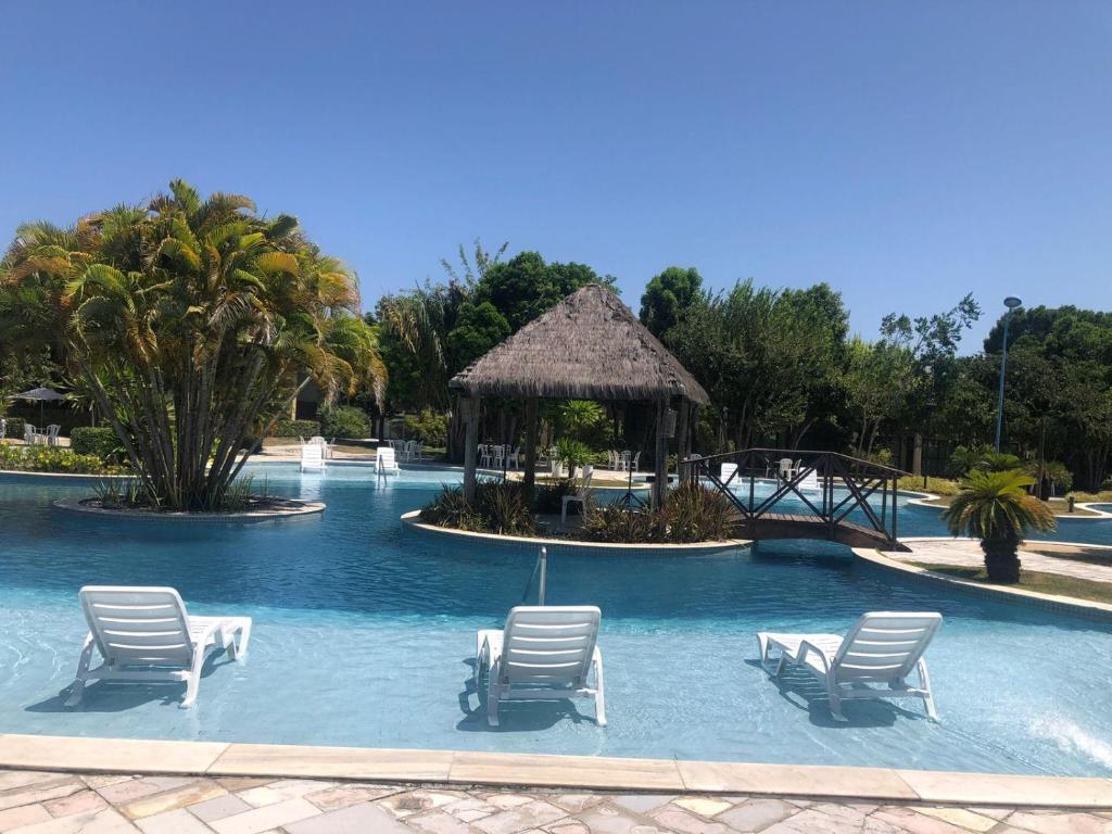 a swimming pool with chairs and a gazebo at Cobertura 3Q ILOA Barra de S Miguel Castelo B Temporada in Barra de São Miguel