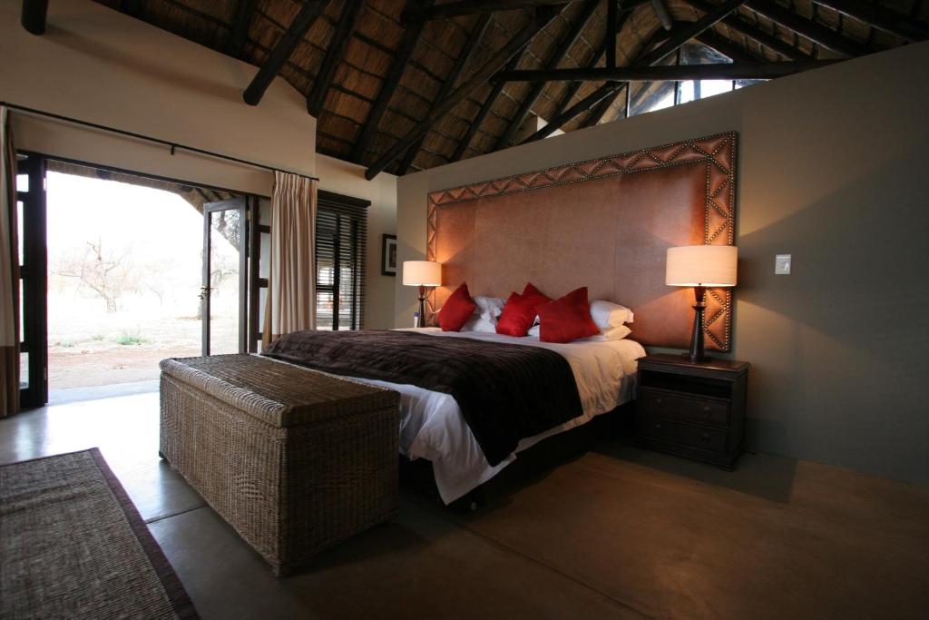 a bedroom with a large bed with red pillows at Buffalo Thorn Lodge in Pilanesberg