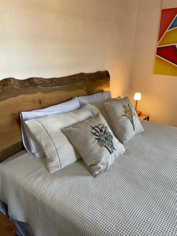 una cama con almohadas blancas encima en Casa Divinas, en Tiradentes